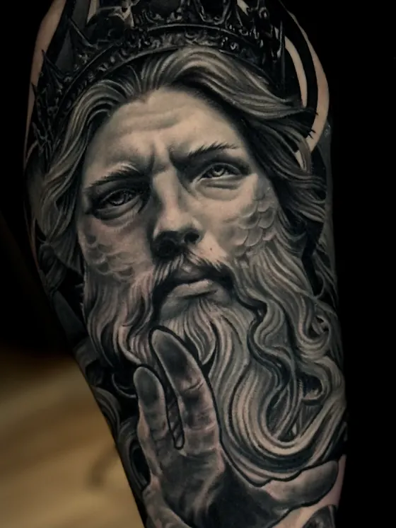 Portrait réaliste noir et gris d'un roi couronné, tatouage avant-bras