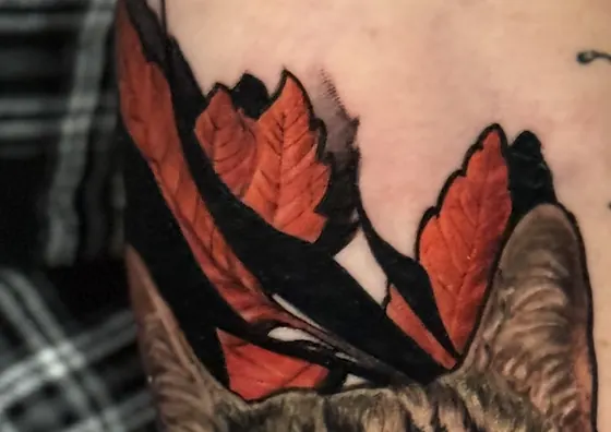 Détail du feuillage automnal encadrant le portrait du chat, tatouage réaliste couleur