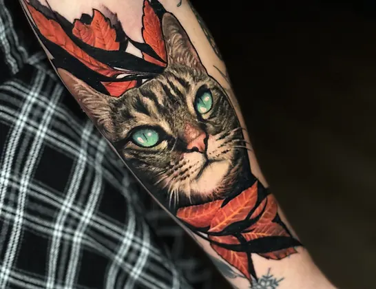 Portrait de chat tigré aux yeux verts, feuillage automnal, tatouage avant-bras réaliste couleur