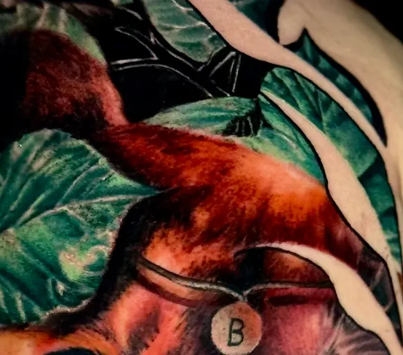 Détail du feuillage et du médaillon lettre B, tatouage réaliste couleur lionne