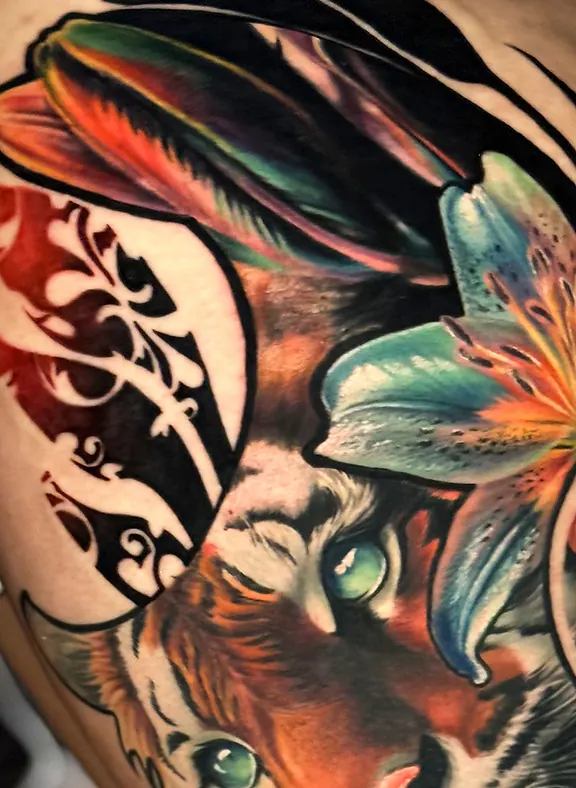 Détail rapproché du regard du tigre, plumes et fleur de lys, tatouage réaliste couleur