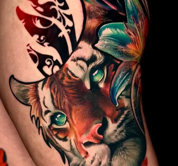 Détail du tatouage tigre sur la cuisse, tribal et fleur de lys, tatouage réaliste couleur